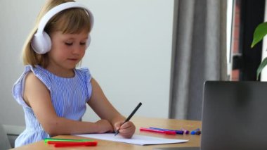 Küçük liseli kız evde video dersi sırasında başını sallayıp kağıda yazı yazıyor. Çalışkan öğrenci laptopta ödev yapıyor. E öğrenim hizmetleri