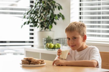Taze çiftlik sütü ve ev yapımı kurabiyelerle gülümseyen bir çocuk. Kahvaltı, süt ürünleri konsepti