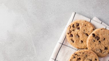Mutfak havlusunda taze pişmiş çikolatalı kurabiyeler. Minimalist gri arka planda. Boşluğu kopyala