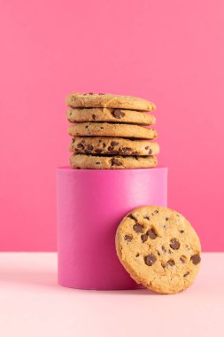 Pembe arka planda üzerinde çikolata parçacıkları olan ev yapımı kurabiyeler. Kurabiyeli moda fotoğrafı, fırın konsepti..