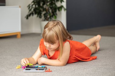 Odaklanmış bir kız renkli bir mantık oyunu oynar. Çocuk gelişimi için oyunlar, mantık oyunu.