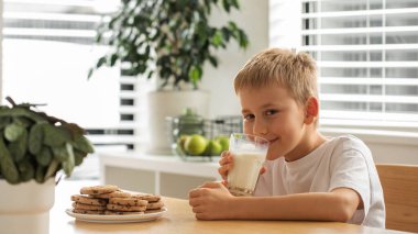Taze çiftlik sütü ve ev yapımı kurabiyelerle gülümseyen bir çocuk. Kahvaltı, süt ürünleri konsepti