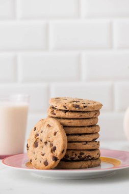 Kurabiyeler bir tabağa yayılır, bir bardak taze süt. Çikolata parçacıklı ev yapımı kurabiyeler. Tarif.