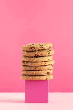 Pembe arka planda üzerinde çikolata parçacıkları olan ev yapımı kurabiyeler. Kurabiyeli moda fotoğrafı, fırın konsepti..