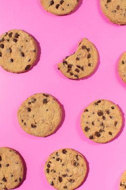 Pembe arka planda çikolata parçalı taze kurabiyeler. Komik bir tatlı konsepti, pastane.. 