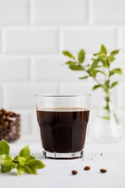 Hafif köpüklü sade kahve, modern beyaz mutfak arka planına göre ayarlanmış, hareketli bir sabah için mükemmel..