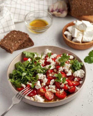 Taze domates ve kişniş soslu peynirli salata ve zeytinyağıyla süslenmiş, sağlıklı bir yemek için mükemmel..