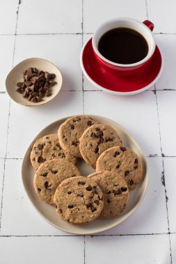 Kırmızı kahve fincanıyla çikolata parçacıklı kurabiyeler. Kahvaltıda. Kafe