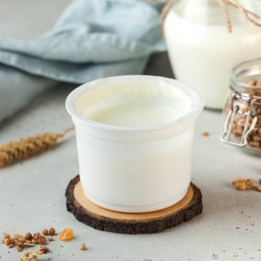 Basit bir beyaz kabın içindeki kremalı doğal yoğurt sağlıklı ve besleyici bir atıştırmalık için mükemmel. Süt