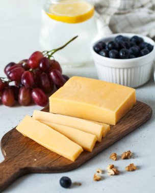 Tahta bir tabakta üzümlü peynir dilimleri, yanında da bir bardak limon suyu.