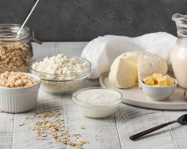Süzme peynir, ekşi krema ve tereyağı beyaz kırsal masada. Mutfakta organik ev yapımı süt ürünleri var. Çiftlik sütü bazlı gıda çeşitleri