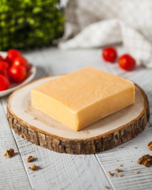 Mutfakta doğranmış ahşap domatesli siyah prens peyniri bloğu. Mutfak masasında bal olan çiftlik sütü ürünü. Süt ürünleri.