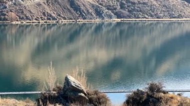 Buzul gölü kıyısındaki kuru çimenler ve kayalar durgun masmavi suyla gökyüzünü yansıtıyor. Suyun kaynağı antik çağlardan kalma. Unutulmaz tatil seyahati