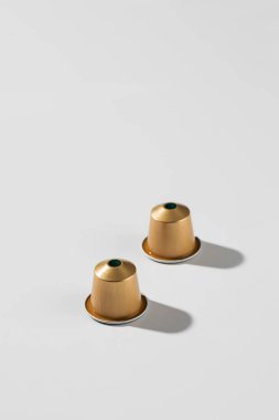 Beyaz arka plandaki altın kahve kapsülleri zarif bir tasarımı ve mükemmel kaliteyi gösteriyor, reklam ve ticari kullanım için tasarlanmıştır. Boşluğu kopyala