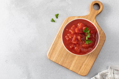 Gri masada meyve suyu ve maydanozla soyulmuş domates konservesi. Mutfaktaki kasede sebze püresi. Lezzetli ev yapımı yemekler. Boşluğu kopyala