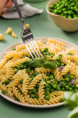 Kadın yeşil bezelyeli vejetaryen makarna yiyor. Hanımefendinin restoranda fusilli ve sebzeli taze sağlıklı yemeği var. Basit mutfak.