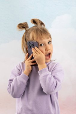 Küçük mutlu kız cep telefonuyla dikkatlice dinliyor. Liseli kız, aletleri öğreniyor. Annemle telefonda yalnız başına konuşuyor.