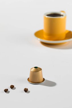 Arka planda fincan ve fincan tabağı olan kahve kapsülü ürünlerin zarafetini ve inceliğini vurguluyor..