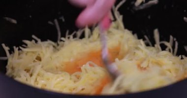 Patatesli krep için malzemeleri karıştır. Bir adam çiğ yumurtayı karıştırıyor ve patatesleri bir kasede rendeliyor. Patatesli krep pişirmek için adım adım video talimatları. 