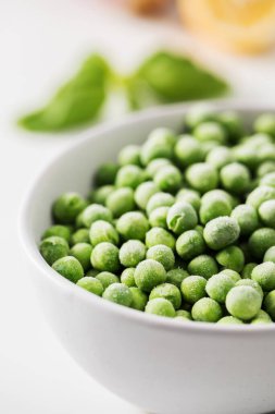 Beyaz arka planda bir kase donmuş yeşil bezelye. Taze ve sağlıklı sebzeler çeşitli mutfak kullanımları için mükemmeldir..