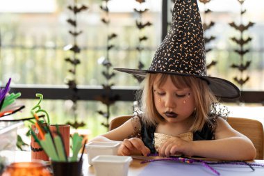 Cadı şapkalı genç bayan daire dekorasyonu yapıyor. Kostümcü kızlar Cadılar Bayramı 'nda farklı karakterlere bürünmeyi severler.