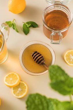 Limon dilimli bal ve bej arkaplanda taze nane yaprakları. Bağışıklık gelişimi için doğal soğuk algınlığı ilacı. Geleneksel tıp üst görünümü