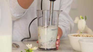 Kadın karıştırıcıda krep için hamuru hazırlayan malzemeleri karıştırıyor. Bayan hızlı ve enerjik bir şekilde smoothie hazırlıyor. Sabah işe gidip gelirken eğlenmek için.