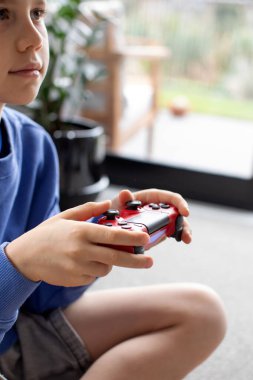 Çocuk elinde bir joystick tutuyor ve dikkatle bir video oyunu oynuyor. Video oyunları konsepti, bir oyun konsolu.
