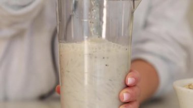 Kadın karıştırıcıda krep için hamuru hazırlayan malzemeleri karıştırıyor. Bayan hızlı ve enerjik bir şekilde smoothie hazırlıyor. Sabah işe gidip gelirken eğlenmek için.