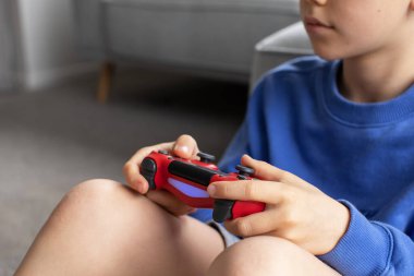 Çocuk elinde bir joystick tutuyor ve dikkatle bir video oyunu oynuyor. Video oyunları konsepti, bir oyun konsolu.