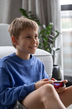 Çocuk elinde bir joystick tutuyor ve dikkatle bir video oyunu oynuyor. Video oyunları konsepti, bir oyun konsolu.