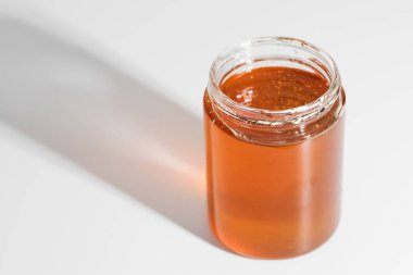 Yüksek kalite görüntü, içinde altın bal bulunan bir kavanozu gösteriyor, kontrollü ışıklandırmada ustalıkla yakalandı..