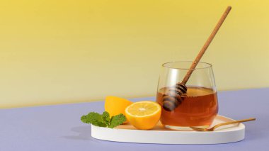 Taze limonlu bal ve tepside nane yaprakları. Sarı arka planda soğuk algınlığı için geleneksel bir ilacın bileşenleri. Bağışıklık sistemini güçlendirmek anlamına gelir