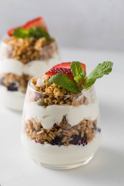 Gevrek taneli yoğurt, lezzetli bir kahvaltı için çilek ve nane yaprağı. Sağlıklı beslenme kavramı.