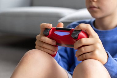 Çocuk elinde bir joystick tutuyor ve dikkatle bir video oyunu oynuyor. Video oyunları konsepti, bir oyun konsolu.