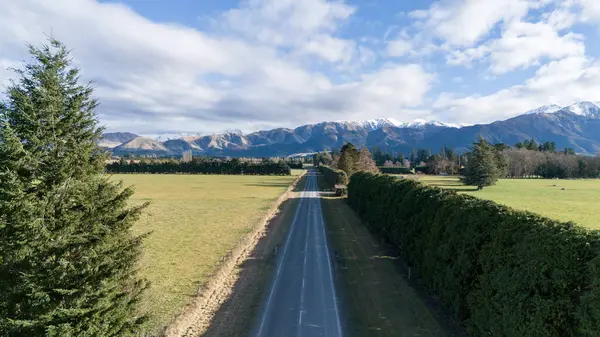 Tarlalar ve sıra sıra ağaçlar boyunca uzanan dağ sırasına giden yol. Yol boyunca mahsul yetiştirmek için tahsis edilmiş araziler. Tarımsal alanlarda seyahat etmek