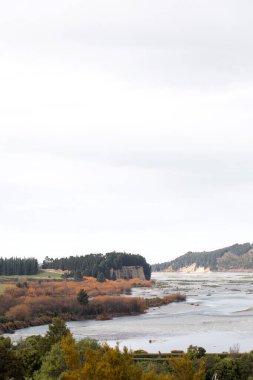 Awe Rakaia nehri bulutlu gökyüzünün altındaki kayalık kıyıların yanından geçiyor. Yeni Zelanda 'nın en büyük örülmüş nehirleri doğa güzelliğinin tadını çıkarmak için yürüyüşçüleri cezbeder. İnanılmaz manzara.