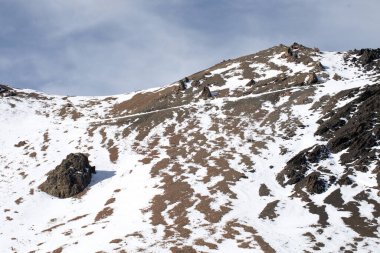 Bulutlu gökyüzünün altında kar ve buzla kaplı eski kayalık dağlar. Antik Hutt Dağı tepesi Yeni Zelanda 'daki kayakçılar arasında meşhurdur. Vahşi bakir yerlere seyahat etmek