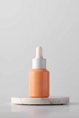 Beyaz arka planda podyumda anti-aging serumu olan bir damlatıcı. Kozmetik konsepti, cilt bakımı.