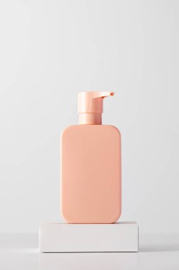 Podyumda logosu olan bir kozmetik ürününün pembe bir maketi. Şampuan, duş jeli. Cilt bakımı kavramı.