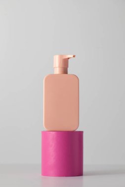 Podyumda logosu olan bir kozmetik ürününün pembe bir maketi. Şampuan, duş jeli. Cilt bakımı kavramı.