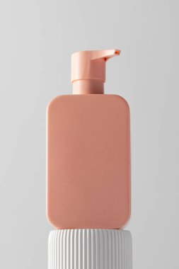 Podyumda logosu olan bir kozmetik ürününün pembe bir maketi. Şampuan, duş jeli. Cilt bakımı kavramı.