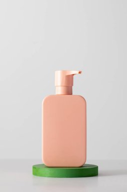 Podyumda logosu olan bir kozmetik ürününün pembe bir maketi. Şampuan, duş jeli. Cilt bakımı kavramı.