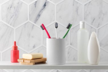 Banyo tezgahında vücut yıkama ürünleri koleksiyonu. Parlak diş fırçaları beyaz tutacakta durur. Sabun ve duş jeli deriyi temizlemek ve beslemek için tasarlanmıştır.