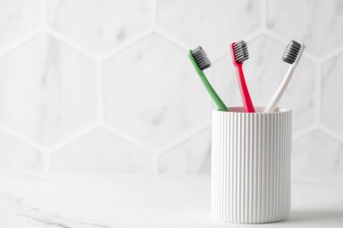Seramik arka planda aile diş fırçaları. Tuvaletteki kişisel hijyen aksesuarları. Diş bakımı malzemeleri evde. Boşluğu kopyala