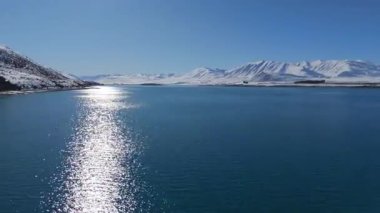 Sakin bir göl manzarası güzel bir şekilde karla kaplı dağlarla çevrilidir. Tekapo Gölü, Yeni Zelanda