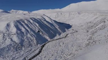 Uçsuz bucaksız, karla kaplı bir dağ sırasının nefes kesici ve çarpıcı manzarası berrak bir gökyüzünün altında dolambaçlı bir nehir.