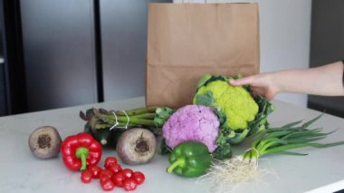 Mutfak masasında kese kağıdıyla çeşitli taze sebzeler vardı. Çiftlik ürünleri konsepti, eve taze sebze teslimatı..