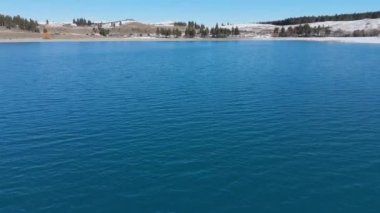Sakin bir göl manzarası güzel bir şekilde karla kaplı dağlarla çevrilidir. Tekapo Gölü, Yeni Zelanda