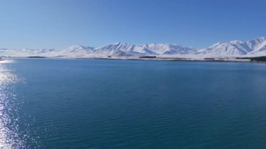 Sakin bir göl manzarası güzel bir şekilde karla kaplı dağlarla çevrilidir. Tekapo Gölü, Yeni Zelanda